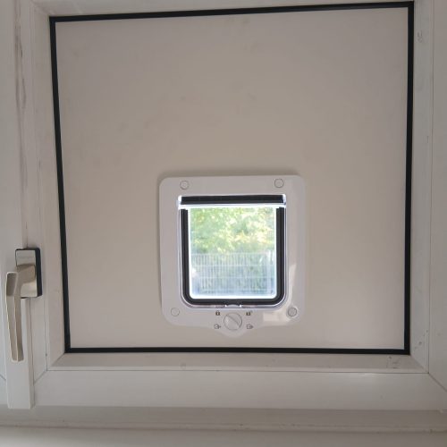 Graz -Wasserdichte 4-Wege-Katzenklappe, sicher und isolierend montiert in einer robusten Aluverbundplatte neben einem doppelverglasten Fenster.